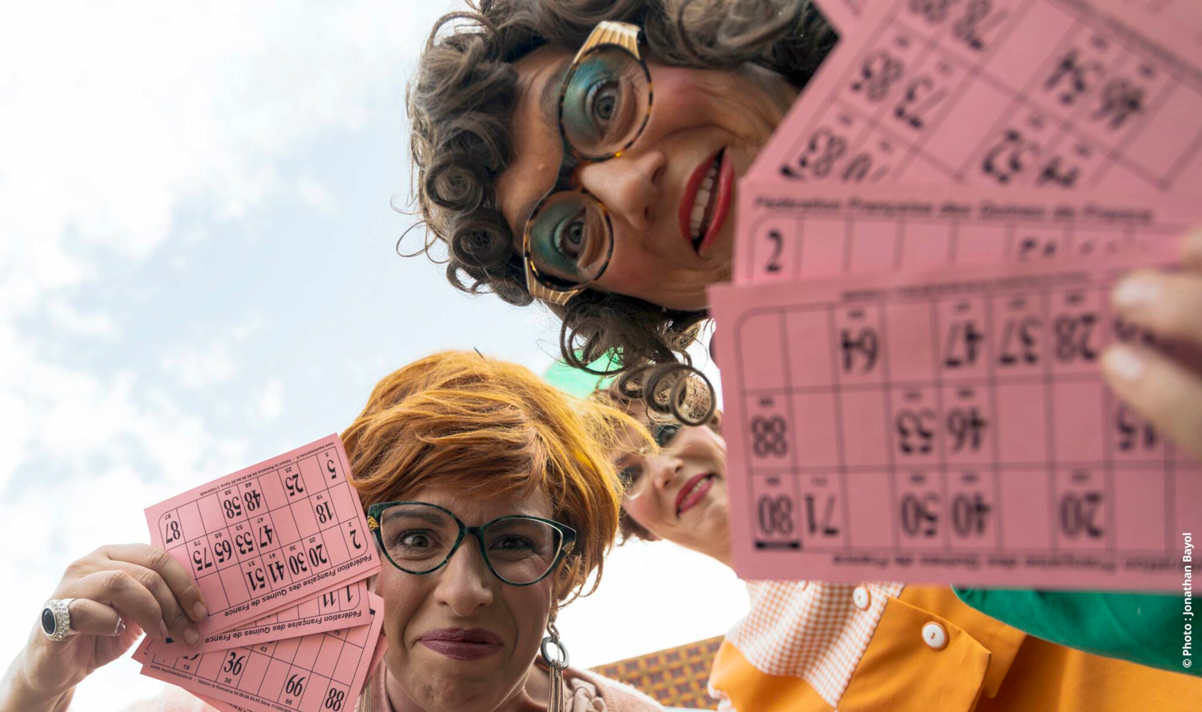 3 femmes regarde l'objectif, cartons de loto à la main.