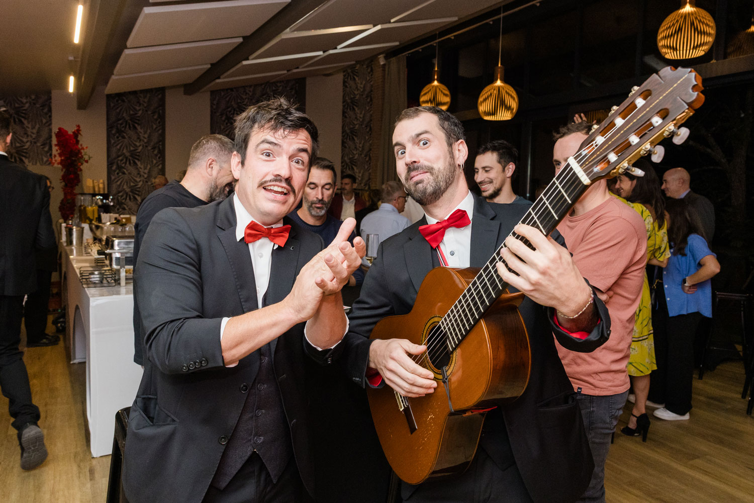 2 musiciens en costard jouent. L'un à la guitare et l'autre chante en tapant dans les mains.