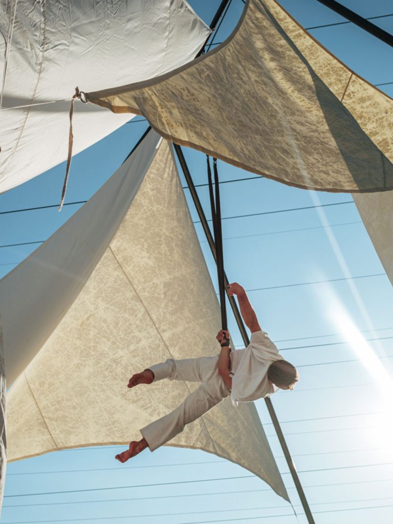 Un voltigeur est suspendu sur un agrée de voiles en toile.