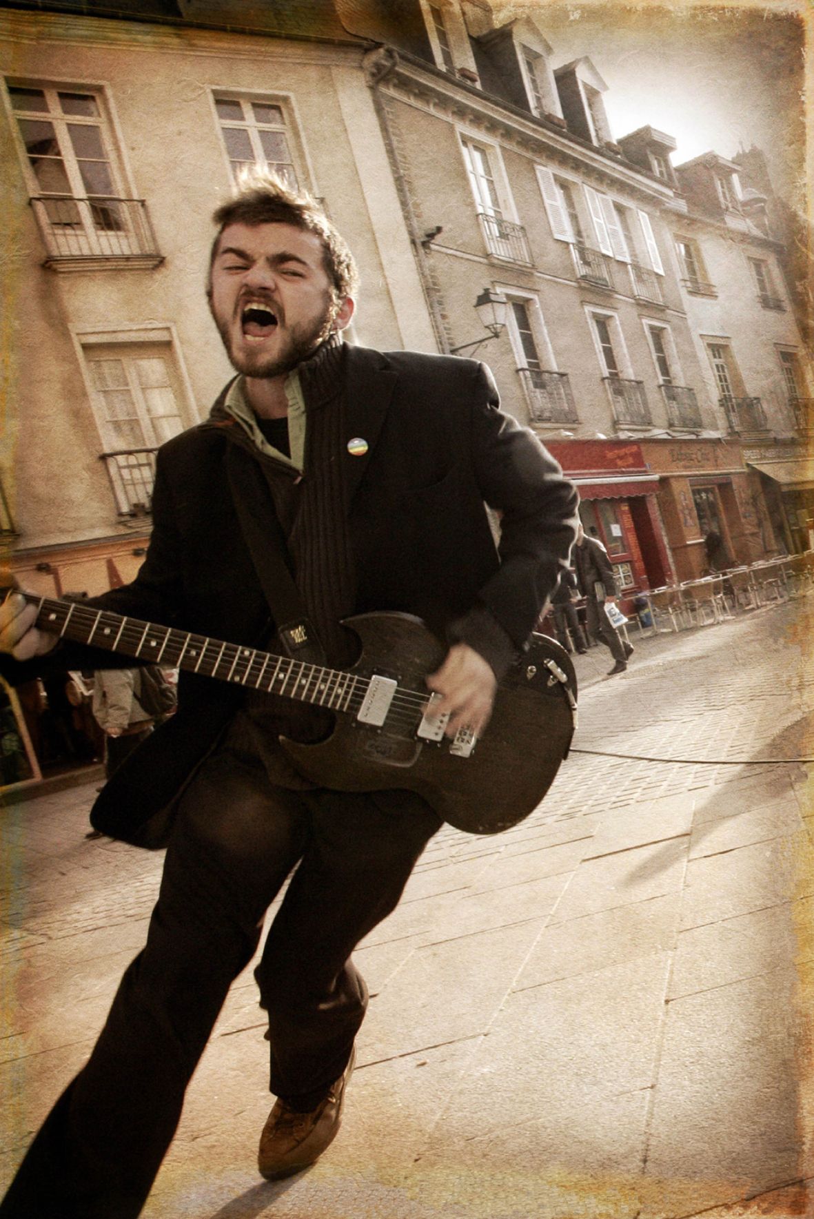 Un homme en costume chante dans la rue une guitare à la main.