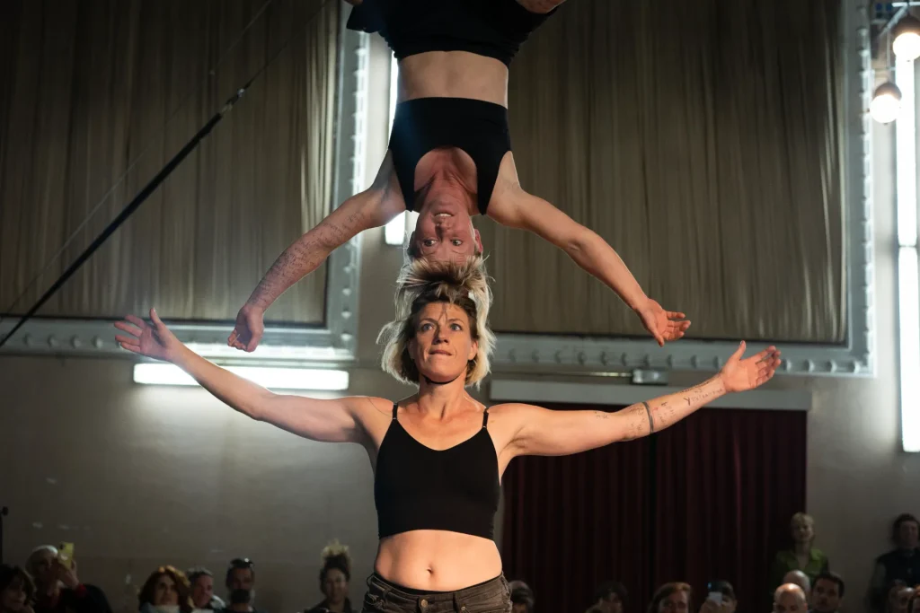 2 femmes font une pyramide en hauteur, tête contre tête.