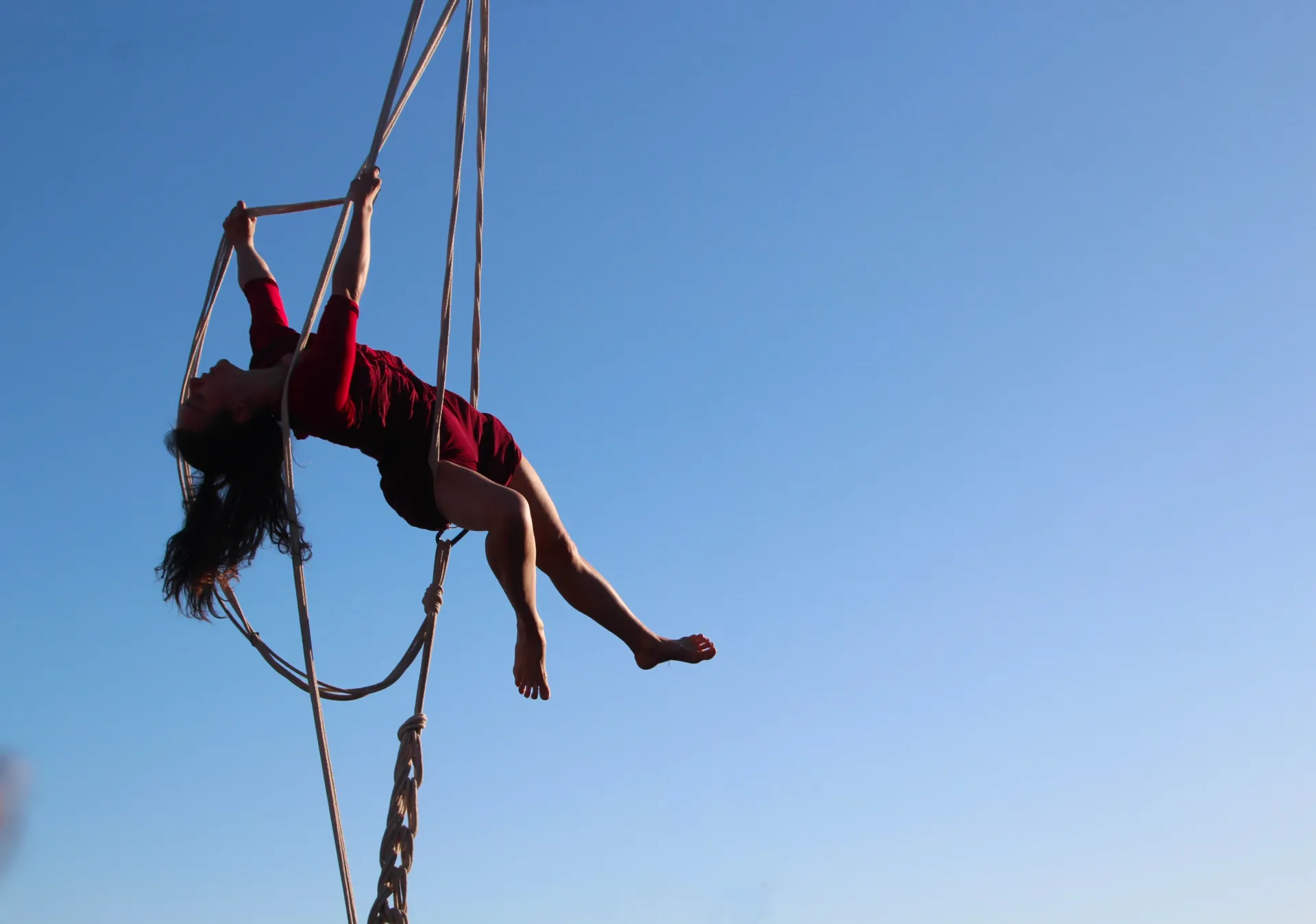 Une femme fait de la voltige avec des cordes dans le ciel.
