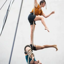 Deux artistes en équilibre l'un sur l'autre, font de la danse sur cordes. L'une est debout. Le deuxième en dessous sur le dos et une jambe enroulée dans une corde.