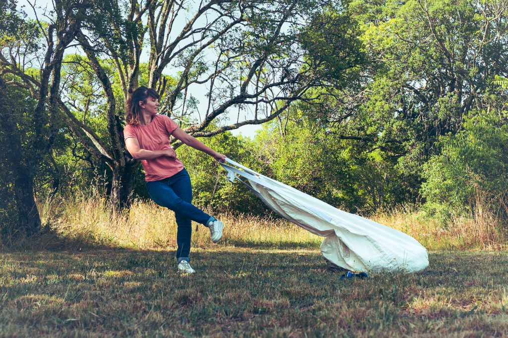 Une danseuse traine un sac dans la campagne, le tout formant des lignes de fuites.