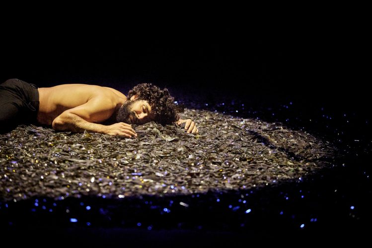 Sur scène, le circassien, torse nu est allongé sur un grand tas de verre qu’il prend comme son oreiller.