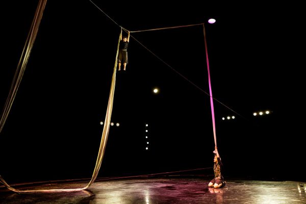 2 danseuses tirent et se suspendent à un long drap. La scène est éclairée en rose et orange.