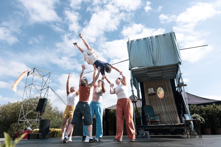 Devant un décor de salon construit en matériaux de récupération, 5 circassiens font un porté.