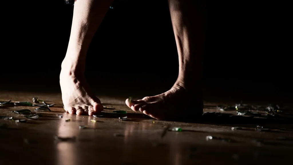 Gros plan sur des pieds nus qui marchent sur du verre.