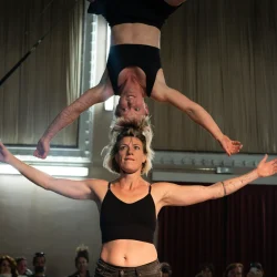 2 femmes font une pyramide en hauteur, tête contre tête.