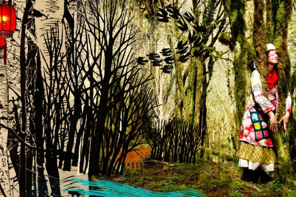 Une comédienne habillée avec des habits colorés, se tient devant un décor de forêt fait en photo et papier.